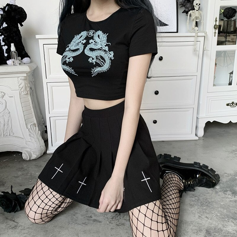 Black Gothic top with dragon print paired with a pleated black skirt and fishnet stockings in a stylish setup.