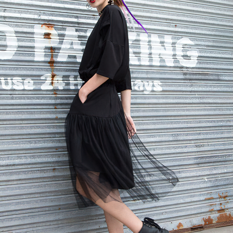 Model in black irregular half-length trousers with mesh layer, showcasing alternative fashion style.