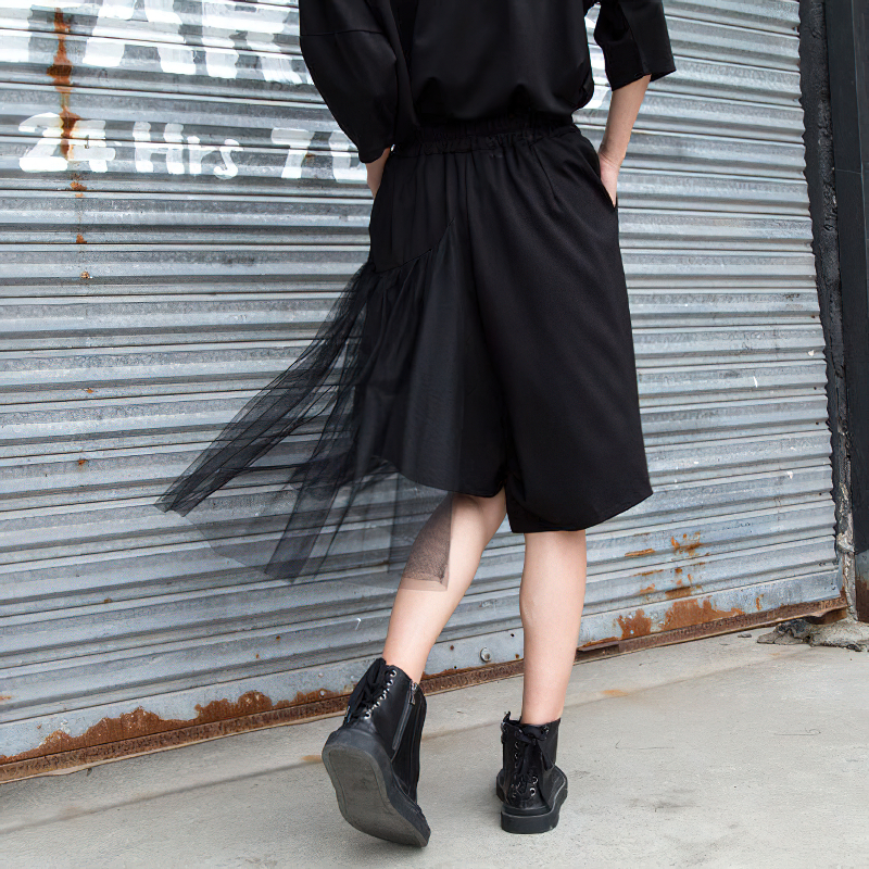 Asymmetrical black loose fit shorts with mesh detail, perfect for alternative fashion and rockstar outfits.