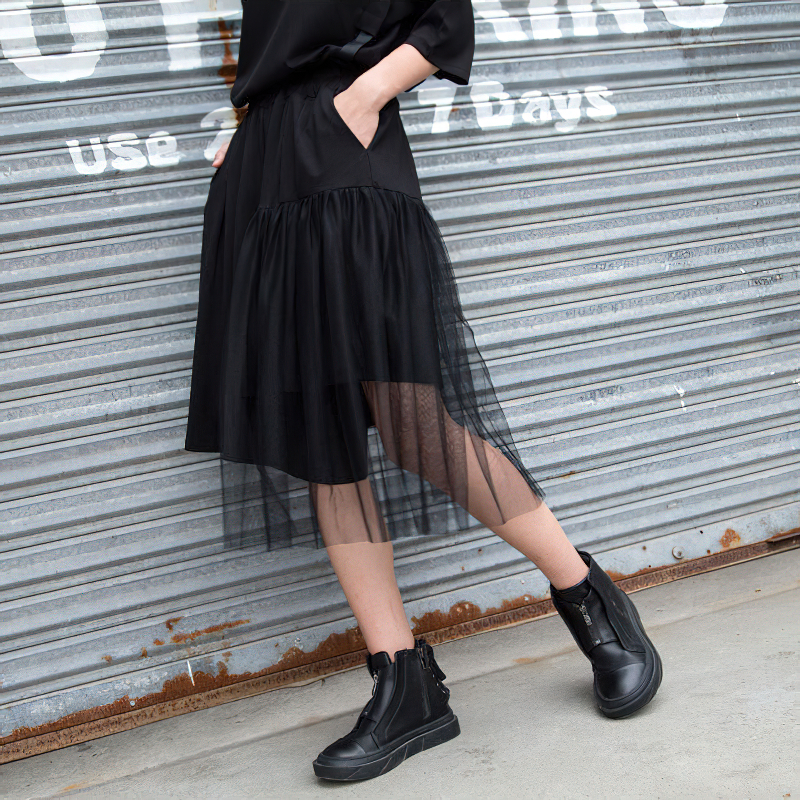 Model showcases black irregular half length trousers with mesh layer and high elastic waist, perfect for alternative fashion.