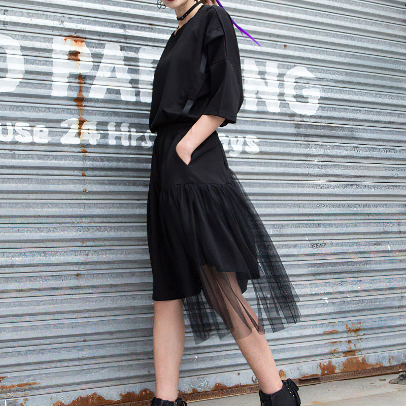 Black asymmetrical half length trousers with mesh overlay, perfect for alternative and gothic fashion.