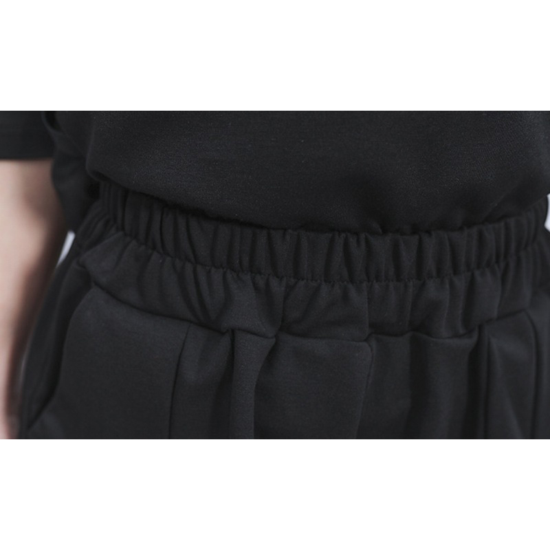 Close-up of black irregular half length trousers featuring high elastic waist, perfect for alternative fashion looks.