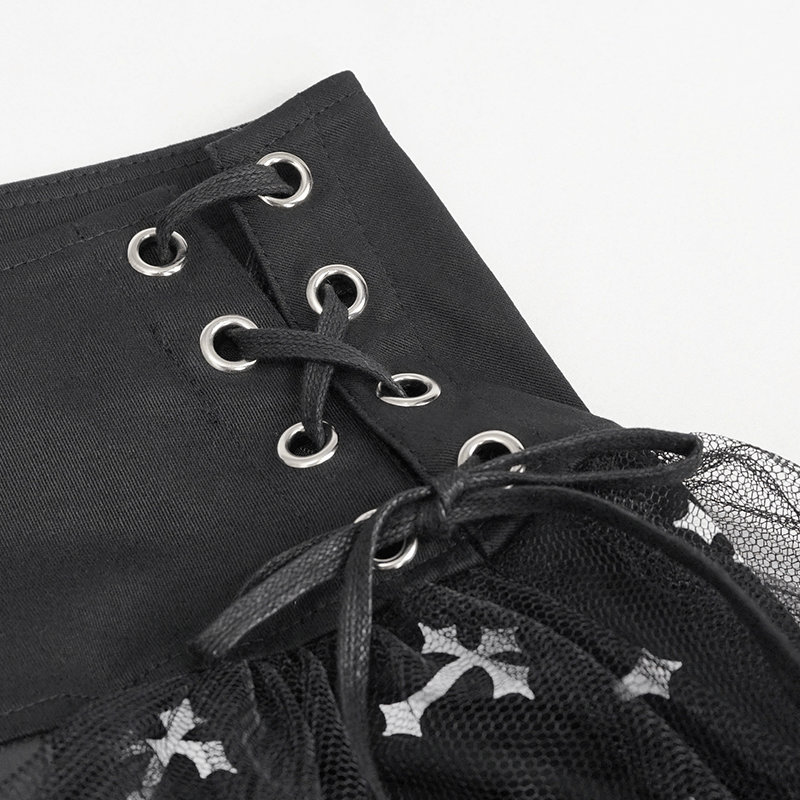 Close-up of black knitted skirt with white crosses, featuring side waist straps and lace-up detailing.