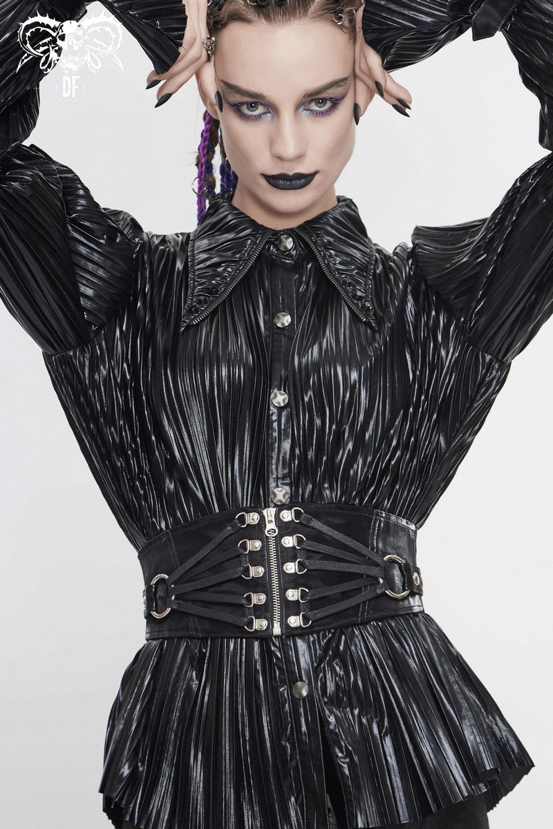 Gothic style black corset belt with silver rivets, worn over a pleated black blouse by a model with bold makeup.