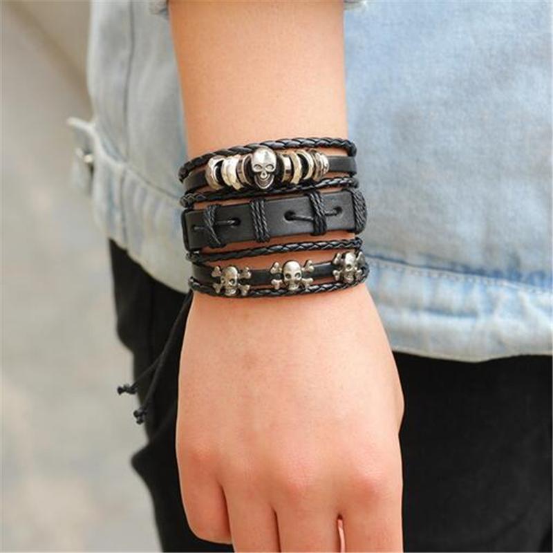 Black leather bracelet set of 6 with skulls and stars, unisex rock style wristband worn on hand.