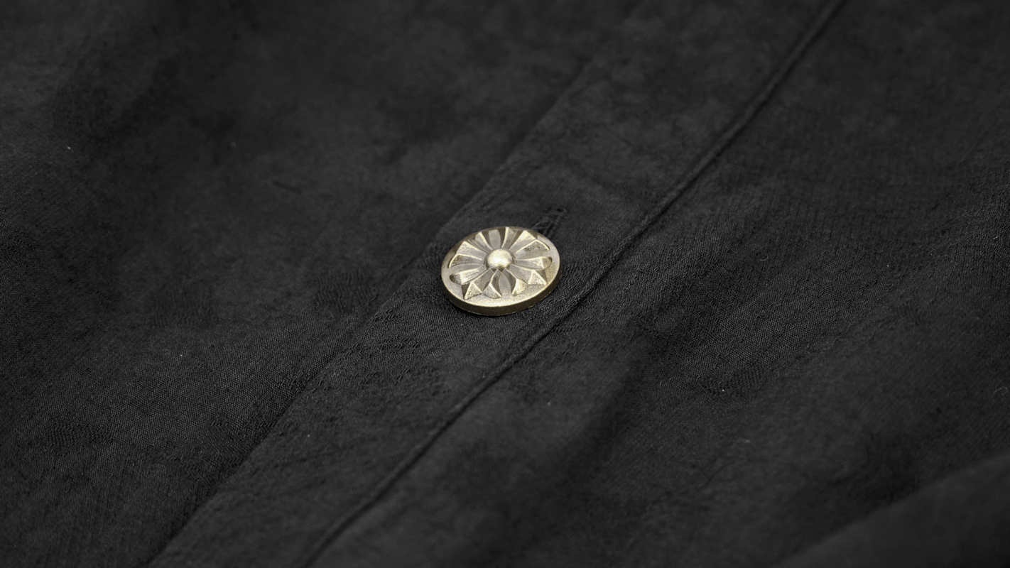 Close-up of a vintage black shirt button showcasing intricate detailing on gothic style fabric.