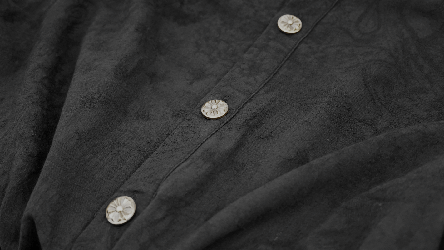 Close-up of elegant buttons on a black gothic style shirt, showcasing vintage design details.