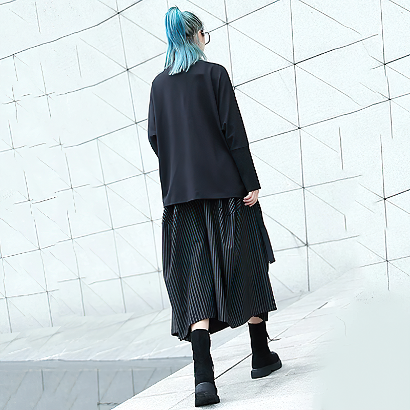 Stylish black long women's skirt with white stripes, paired with a black top and trendy boots, exuding streetwear fashion.