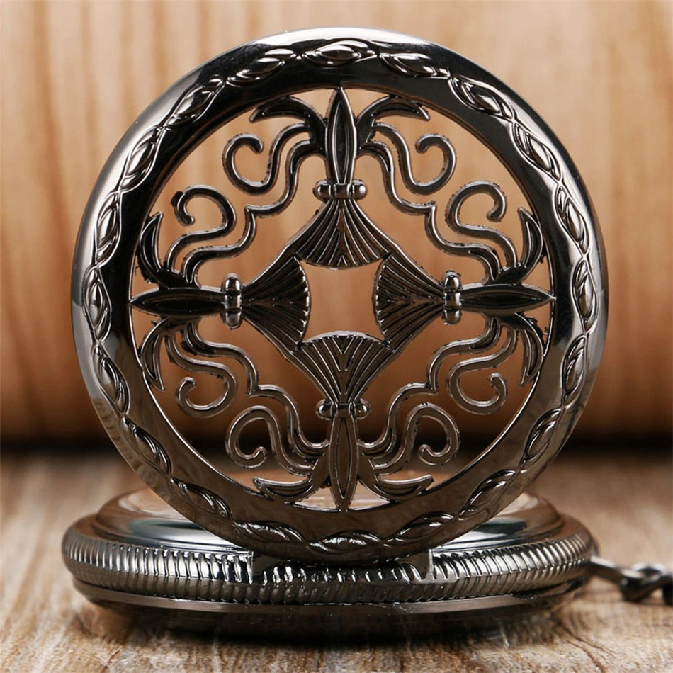 Antique black mechanical pocket watch with intricate design and Roman numerals on a wooden background.