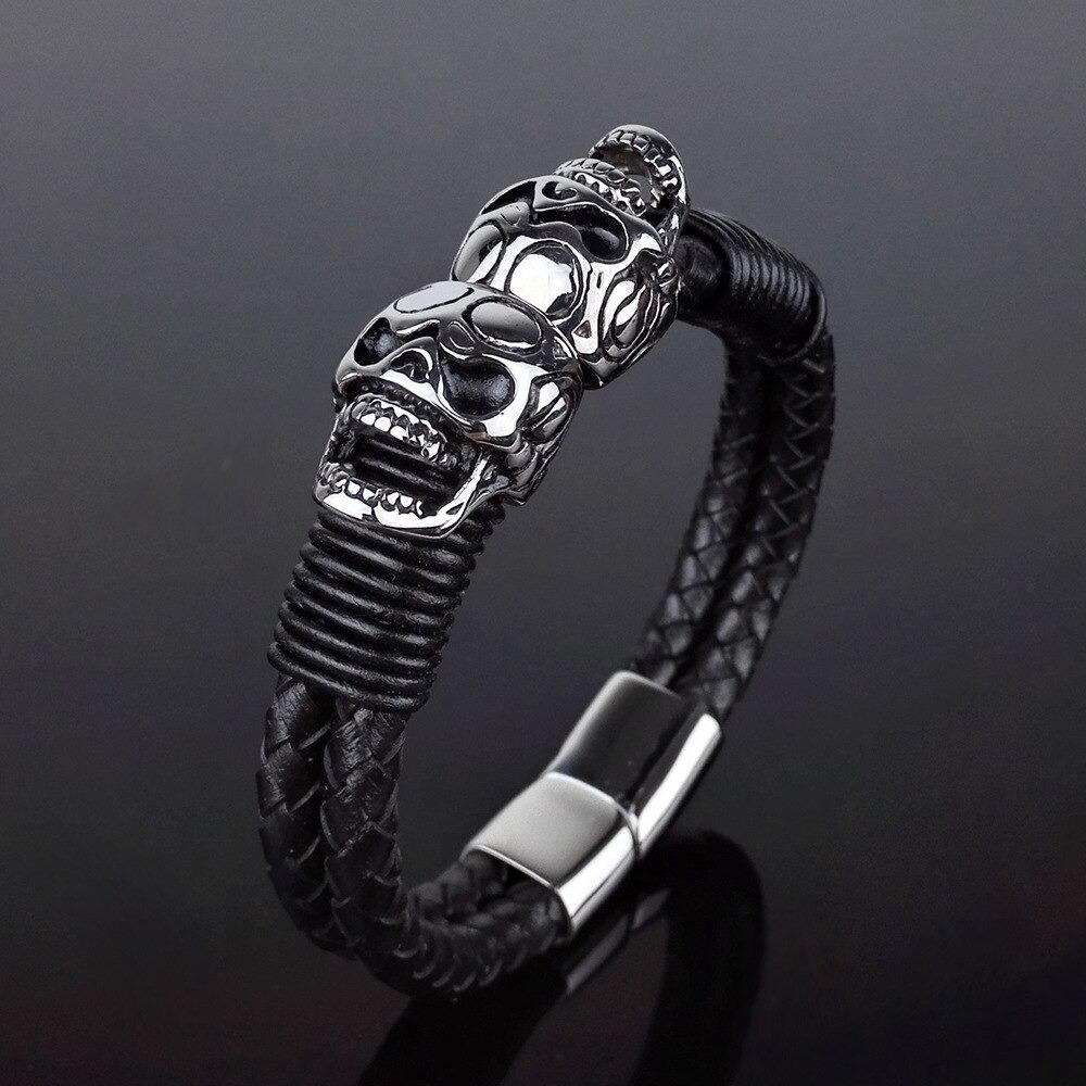 Black braided leather bracelet featuring stainless steel skulls, perfect for punk rock style and gothic fashion.