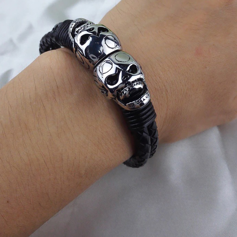 Black men's braided leather bracelet featuring stainless steel skulls, perfect for gothic and punk rock styles.