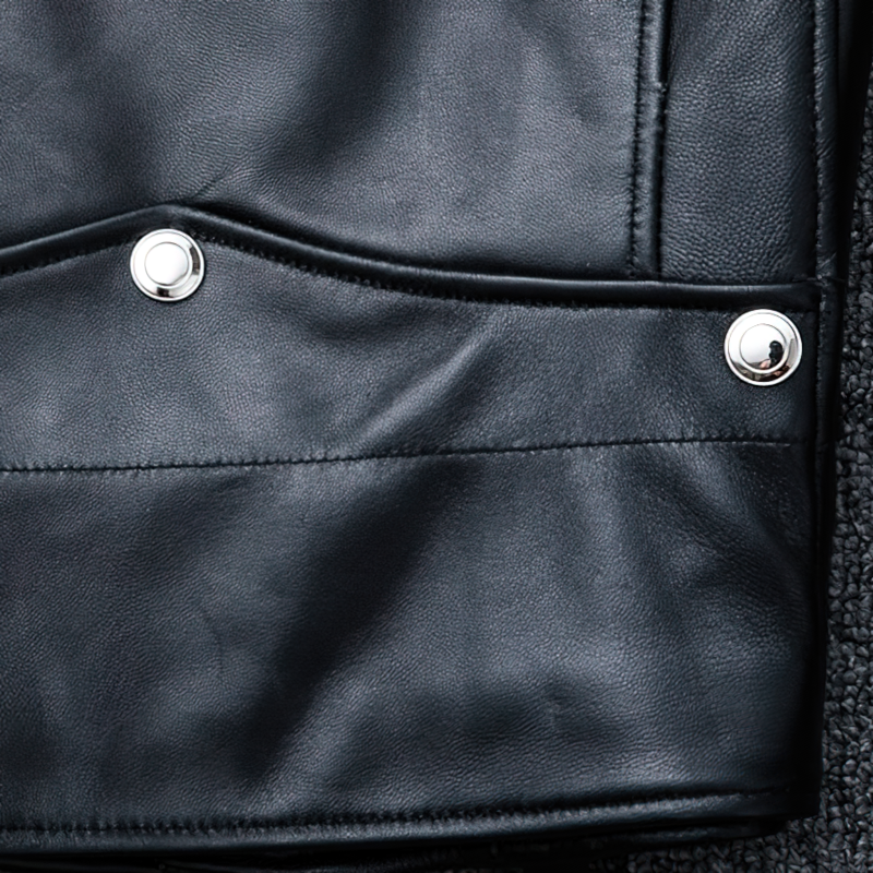 Close-up of a black genuine leather jacket featuring silver snap buttons and stylish pockets.