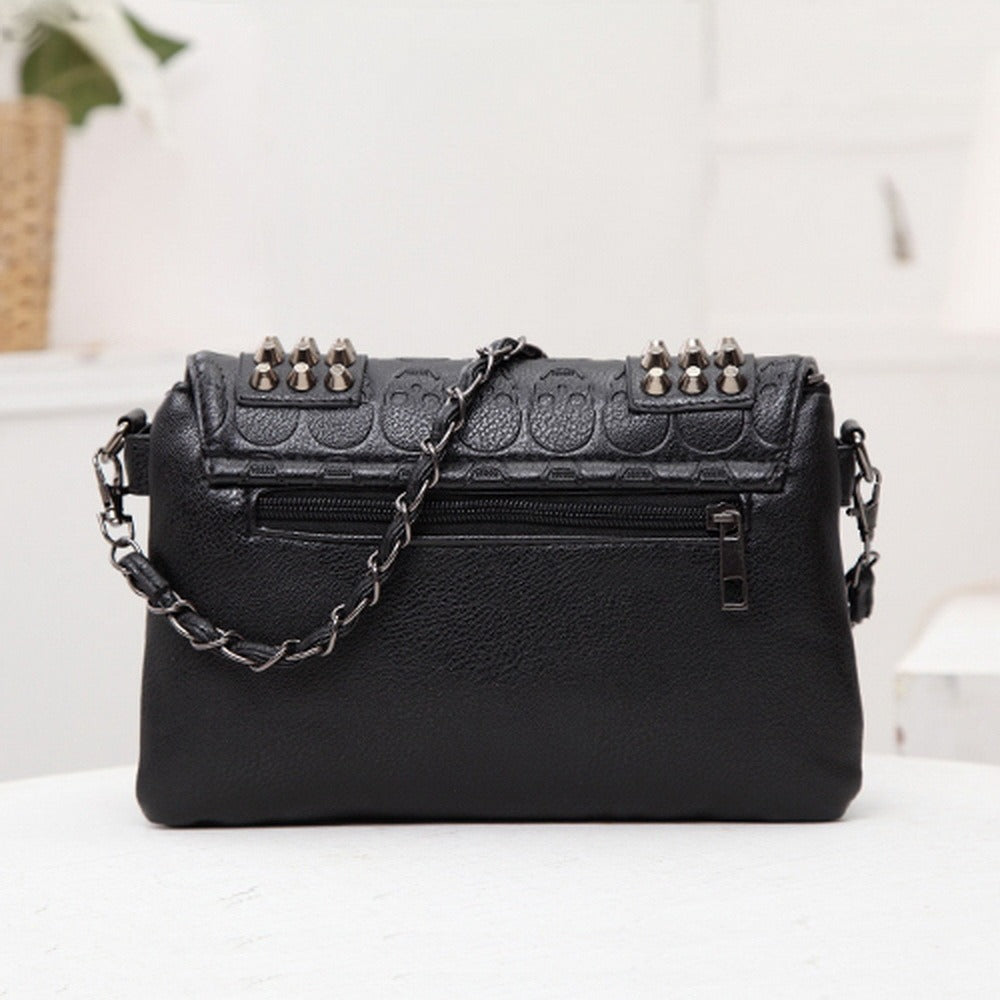 Black messenger bag with skull design, studs, and chain strap, perfect for a gothic style.