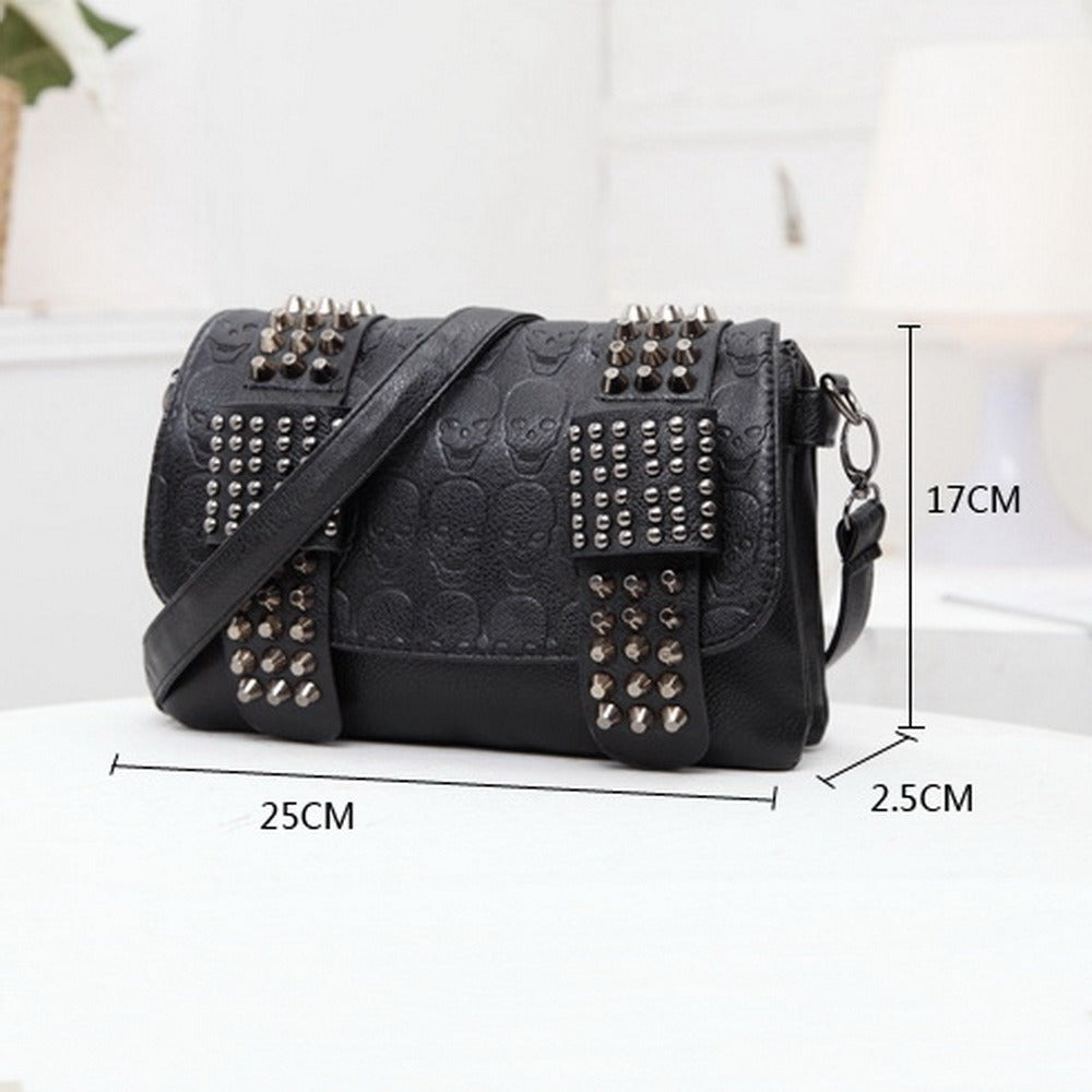 Black messenger bag with skulls and rivets, featuring zippers and pockets, perfect for gothic fashion.