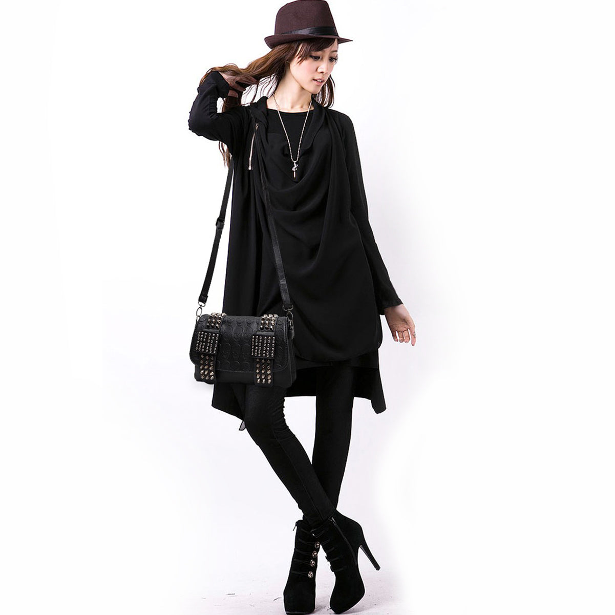 Chic woman in black outfit with a black messenger bag featuring skulls and rivets, exuding a gothic rock style.
