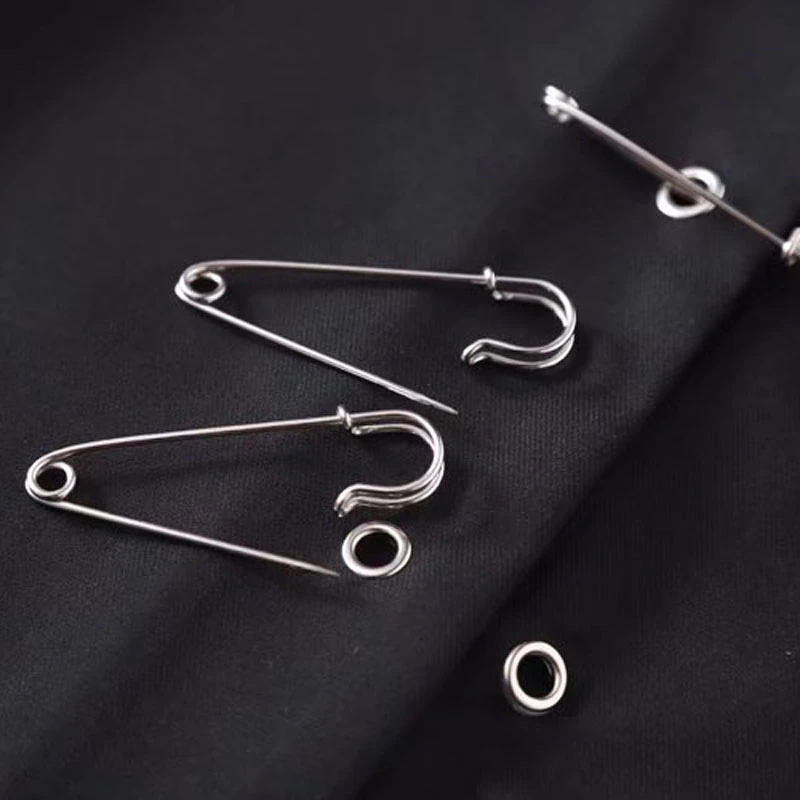 Close-up of silver safety pins on black fabric, perfect for adding vintage flair to outfits.