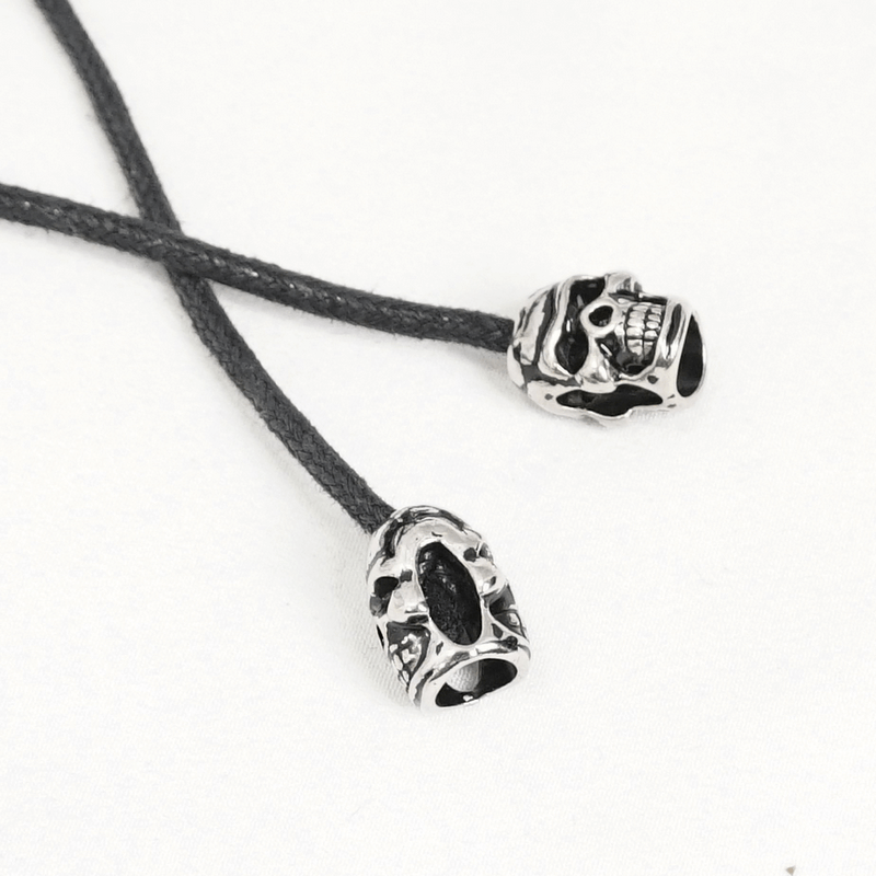 Silver skull zipper pulls on black cord, perfect for a gothic style or edgy fashion accessory.