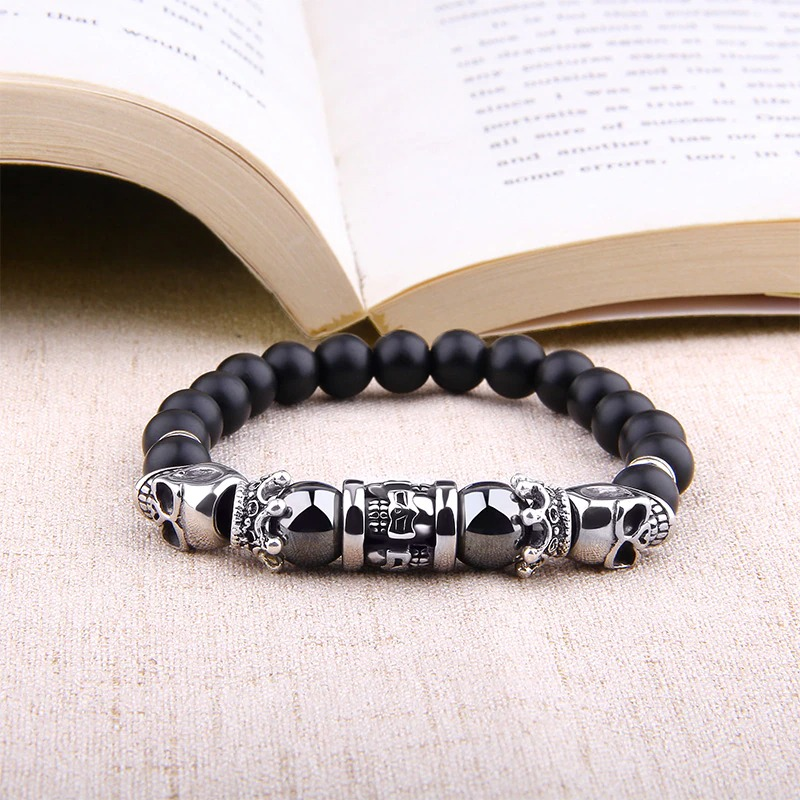 Black Onyx stone skull head bracelet on a surface next to an open book, highlighting its punk style.