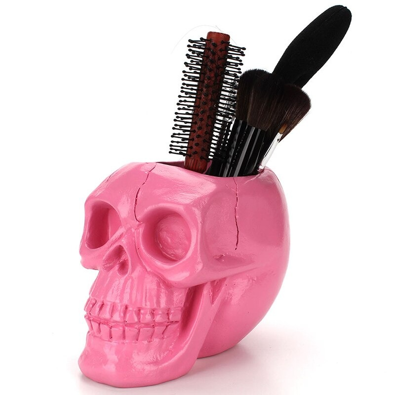 Pink skull pen holder storing brushes and accessories, perfect for Halloween decor and office organization.