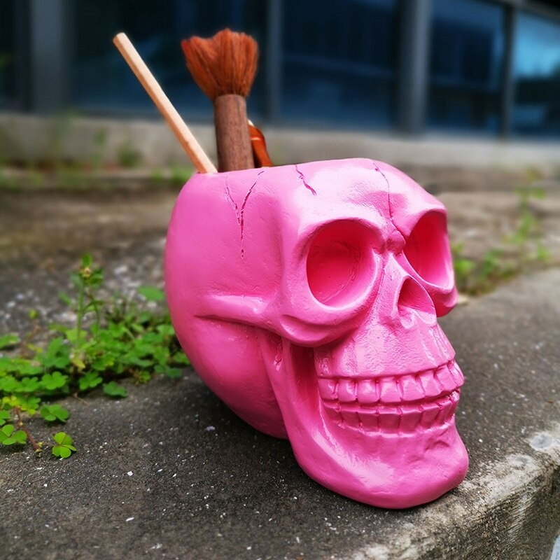 Pink skull pen holder with brushes and pencils, perfect for Halloween decor and office storage.