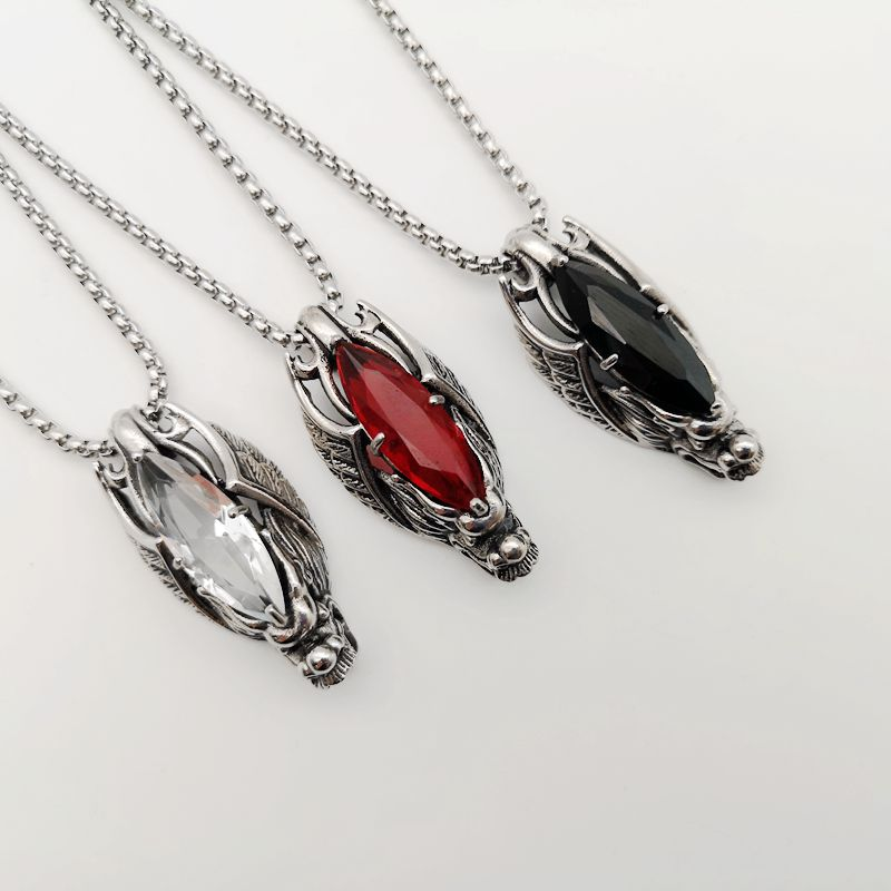 Three dragon head pendant necklaces in silver, red, and black stones against a neutral background.