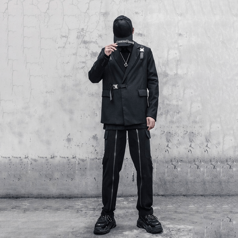 Stylish man in black cargo pants and blazer, showcasing alternative apparel with modern zip details against a textured wall.