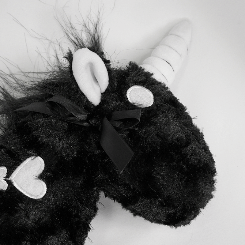 Close-up of a black plush unicorn handbag featuring white bones pattern and a sleek black bow, perfect for gothic fashion.