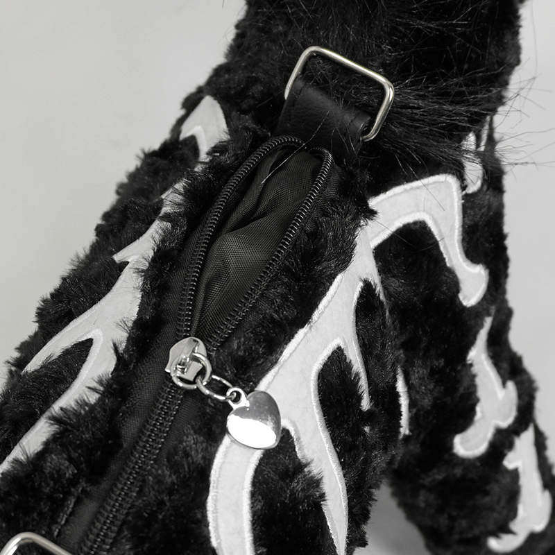 Close-up of a black plush unicorn handbag, featuring a silver zipper and gothic white bone pattern accents.