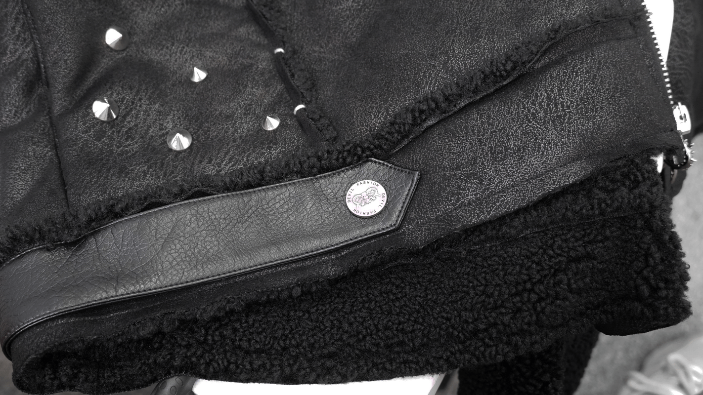 Close-up of a black PU leather jacket featuring studs, buckles, and a cozy fur collar, perfect for punk style.