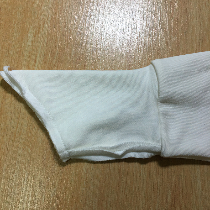 Close-up of a white hoodie sleeve showing stylish cut and stitching details for unique fashion statement.