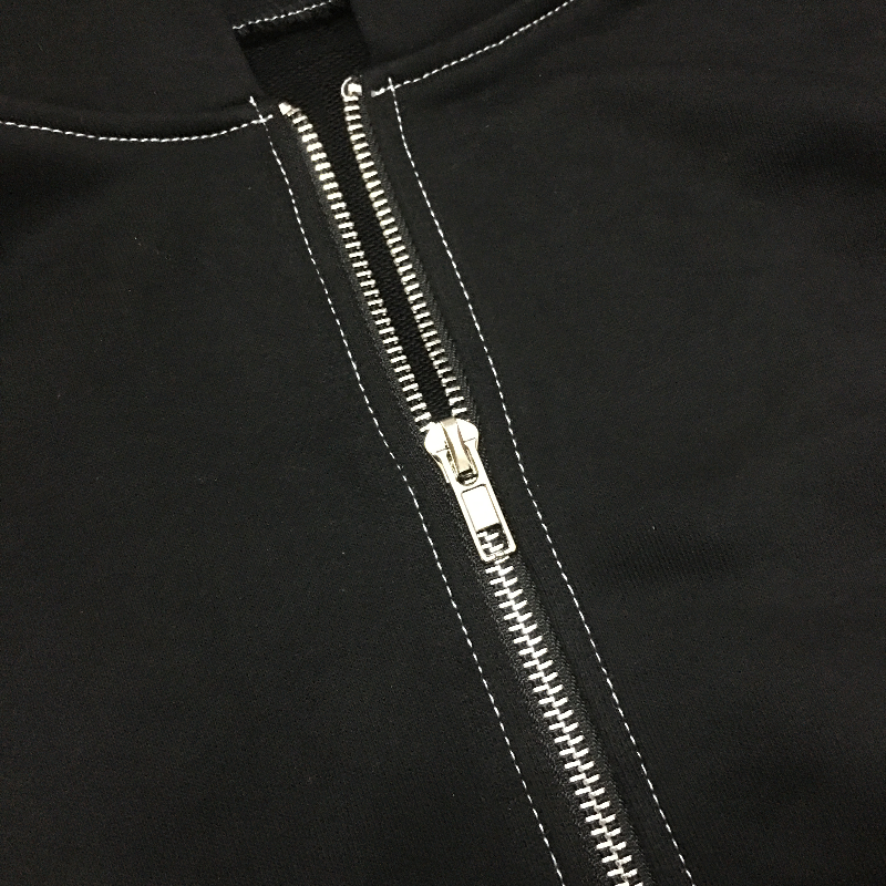Close-up of a black zipper on a pastel goth hoodie with contrasting stitching details.