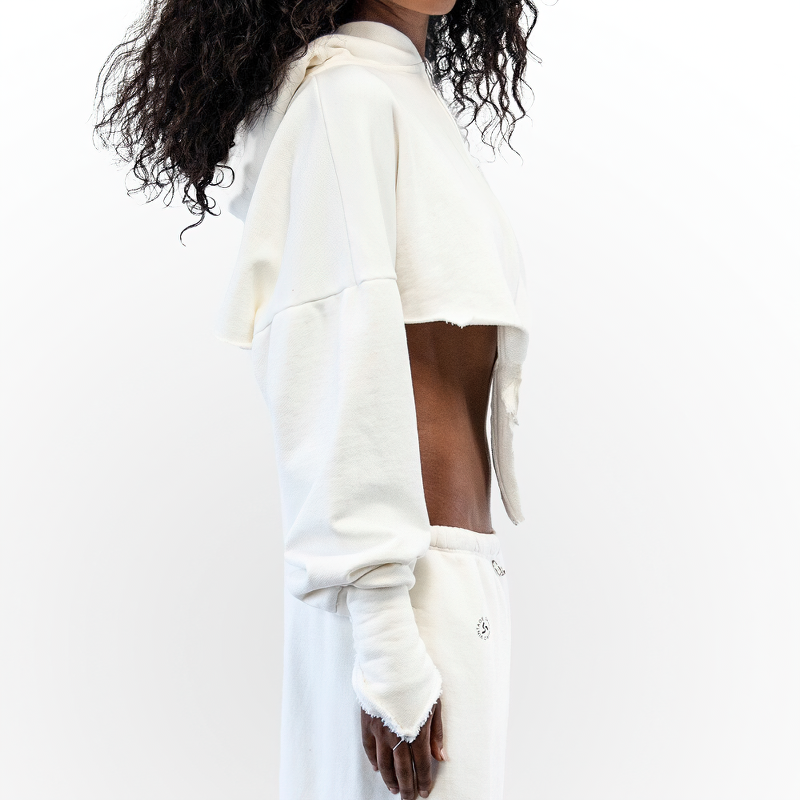 Side view of a model wearing a cropped white hoodie with unique finger details, showcasing a stylish grunge vibe.