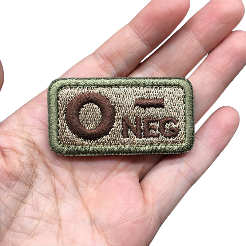 Unisex O- Negative blood type military patch held in hand, embroidered in brown and green, stylish tactical accessory.