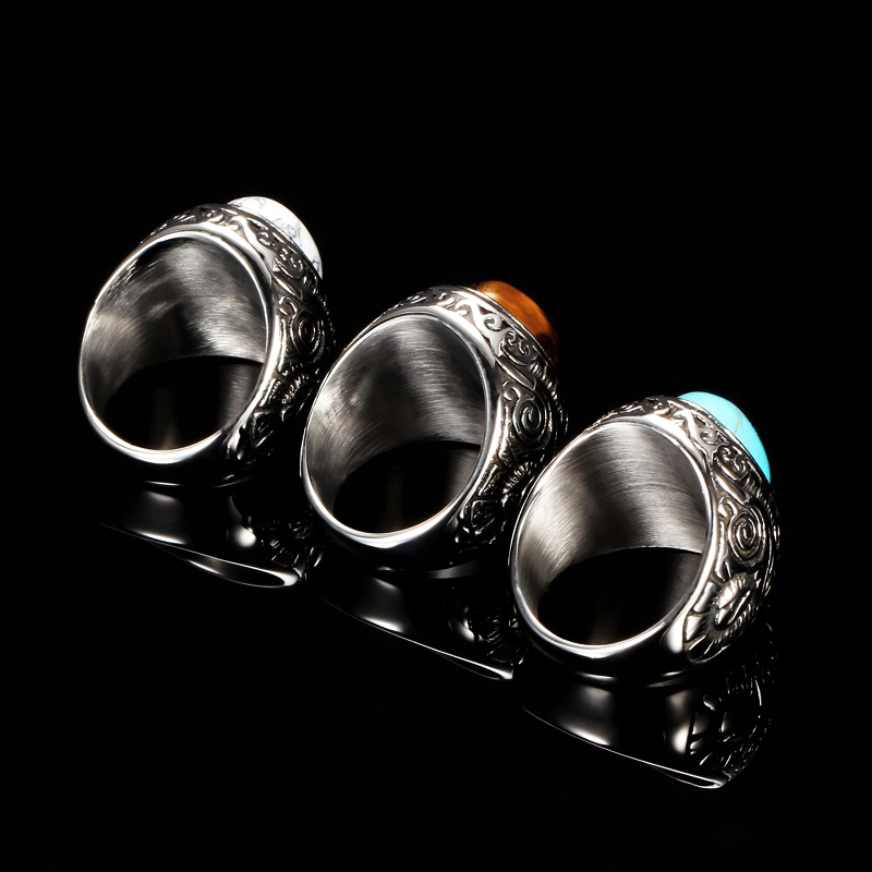 Three vintage unisex stainless steel rings with colorful stones on a black reflective surface.