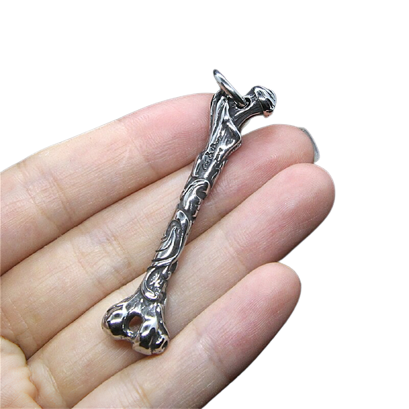 Hand holding a unisex stainless steel bone pendant, showcasing gothic rock style jewelry.