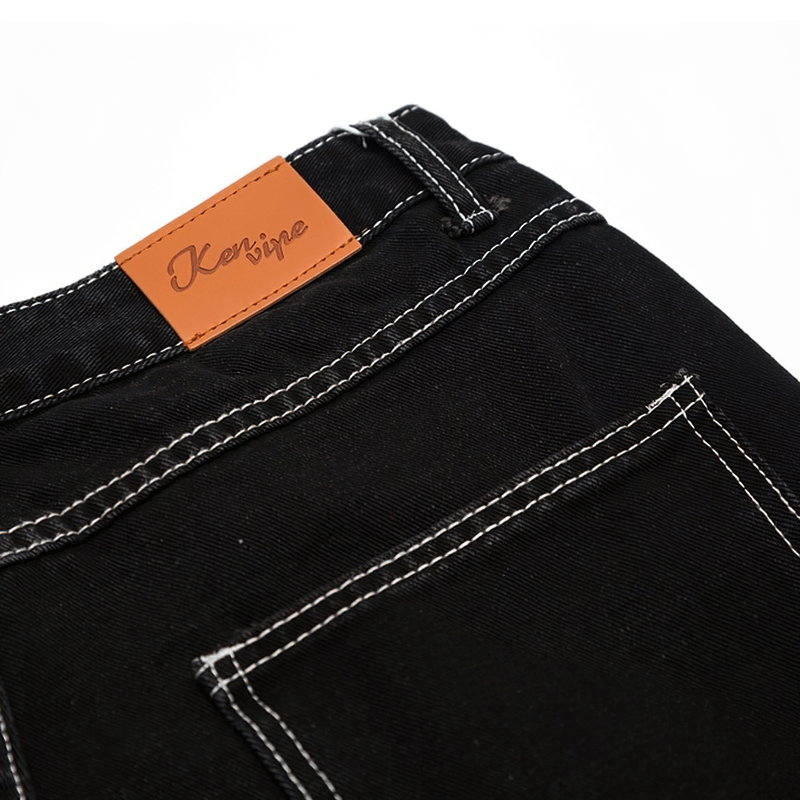 Close-up of black men's jeans with a bone print and stylish leather label by Kerbine on the waistband.