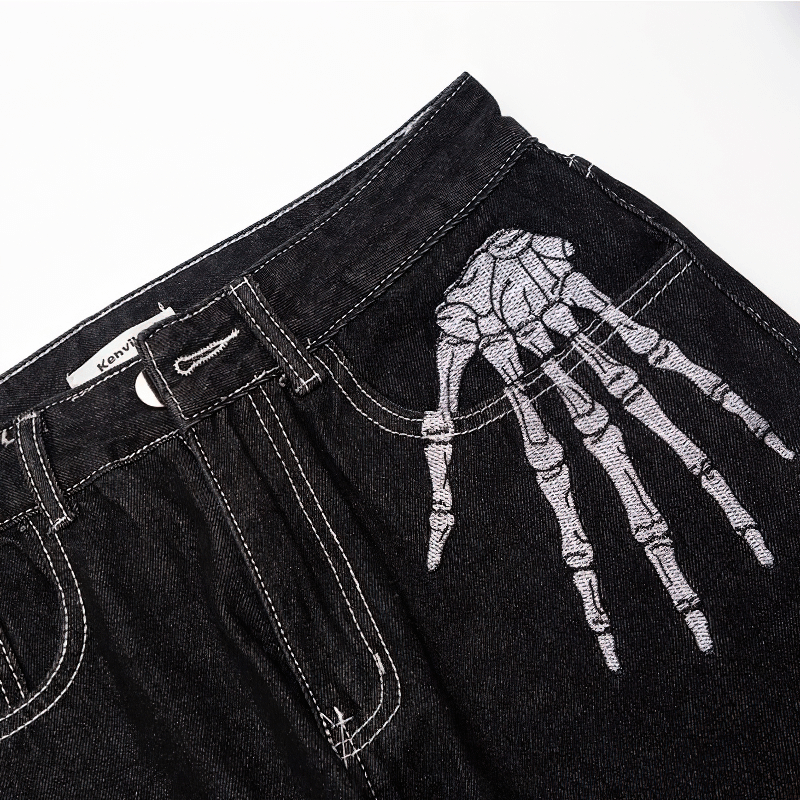 Bone print men's jeans displaying a stylish skeleton hand design on the pocket, perfect for alternative fashion lovers.