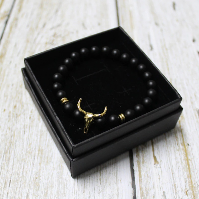 Stylish men's bracelet with black beads and gold bull skull bead showcased in a gift box.