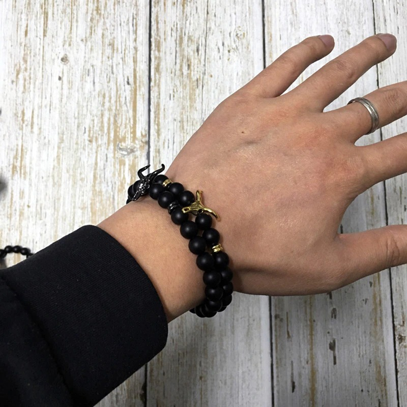 Stylish men's bracelet with black beads and gold accents worn on a hand, showcasing modern men's jewelry.