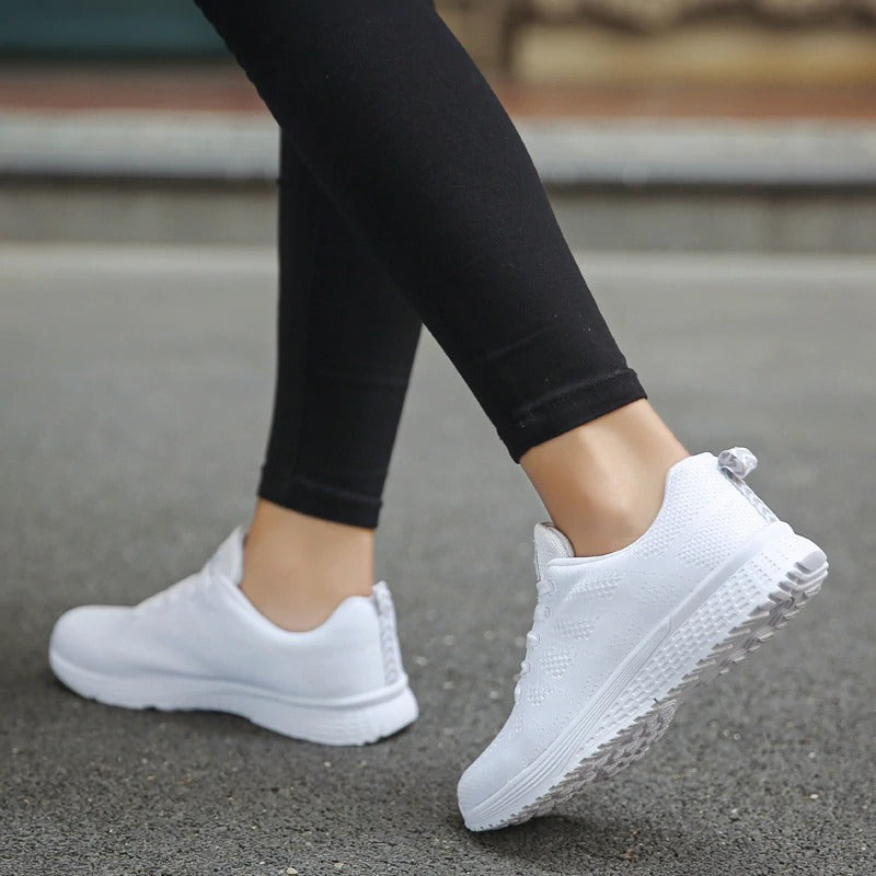 Woman wearing breathable white mesh lace-up sneakers, paired with black leggings, showcasing comfort and style.
