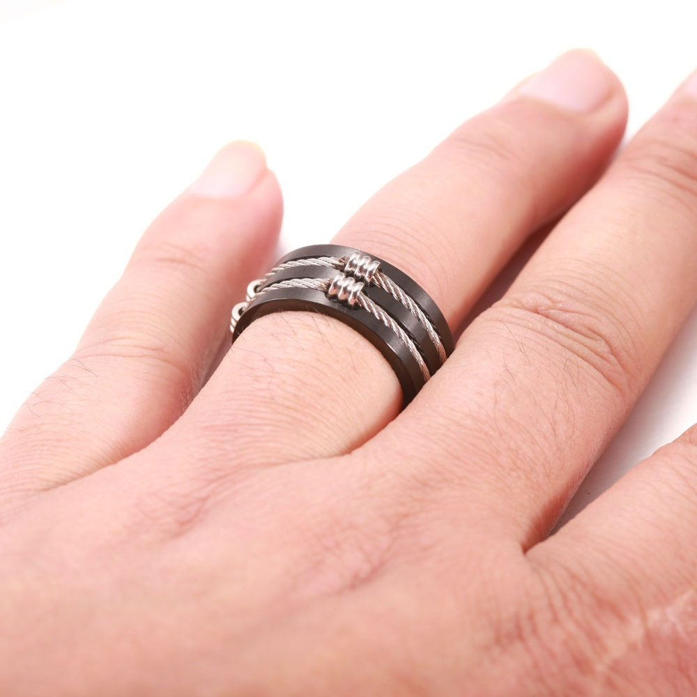 Brushed stainless steel unisex rings with cable wire worn on a hand, showcasing modern alternative jewelry style.