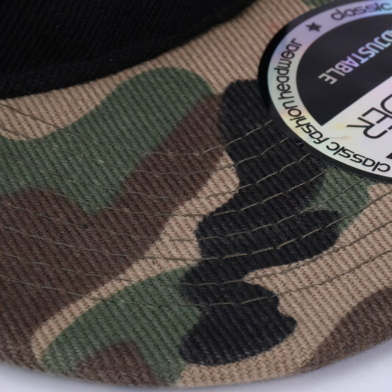 Close-up of a camouflage snapback cap showing textured patterns in green, brown, and black fabric.
