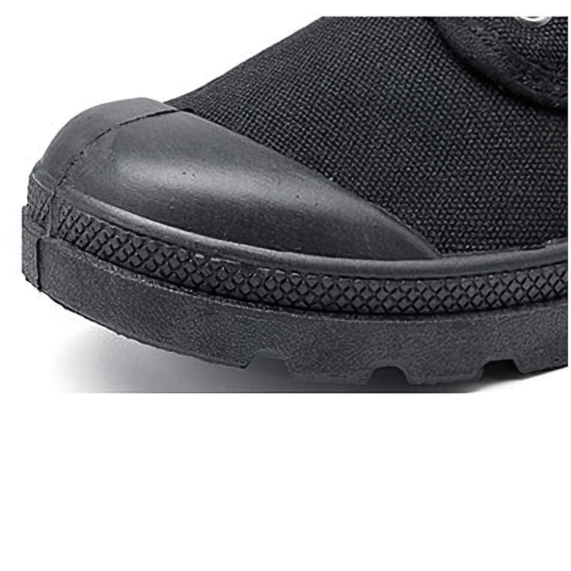 Close-up of black canvas lace-up boot showing durable rubber sole and reinforced toe for military-style comfort.