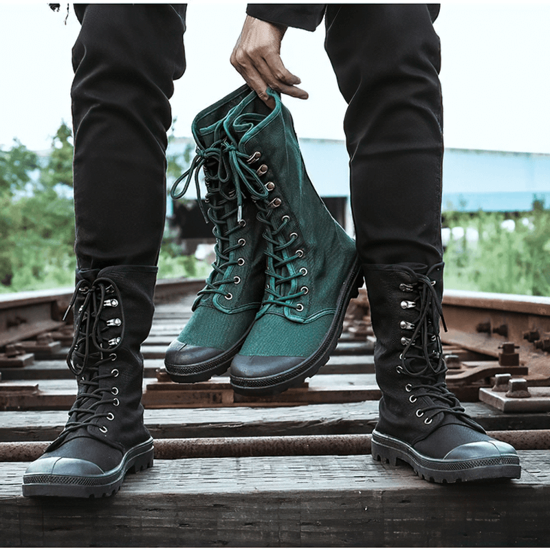 Stylish canvas lace-up boots in black and green displayed outdoors on rustic wooden tracks.