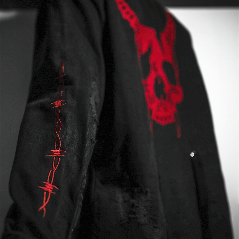 Black denim jacket for men featuring a striking red skull print and unique stitched details on the sleeve.