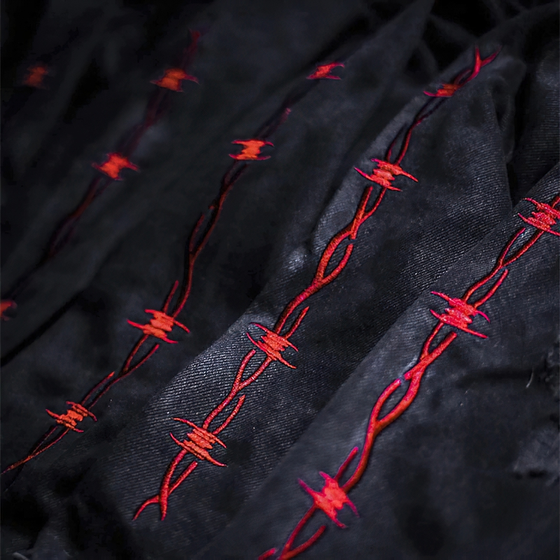 Close-up of black fabric with intricate red barbed wire embroidery, showcasing gothic fashion details.