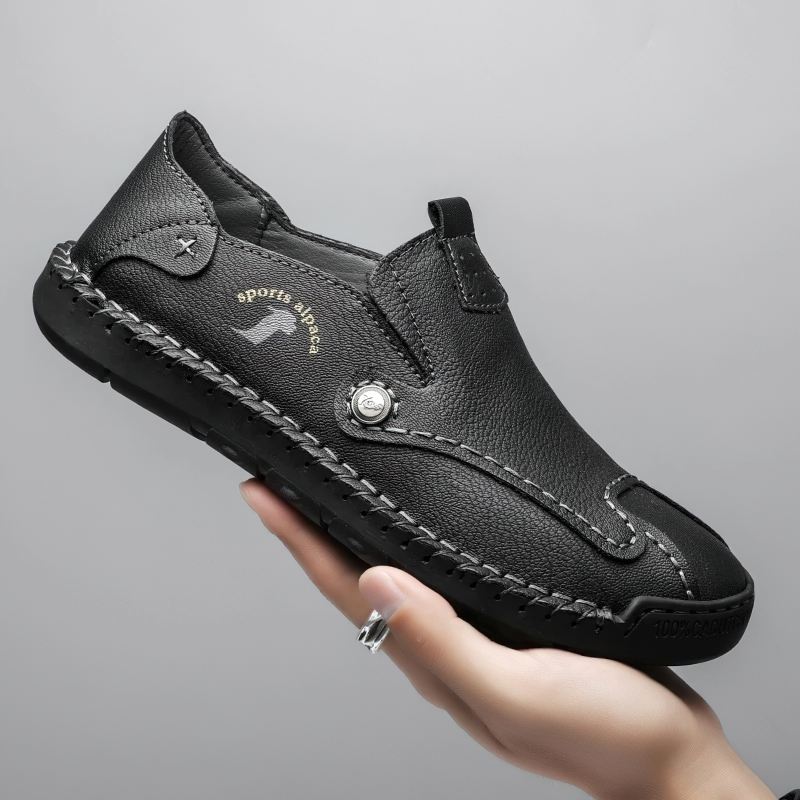 Stylish black PU leather sports loafers held in hand, featuring comfortable design and flexible sole for casual wear.