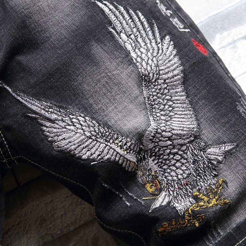 Close-up of eagle embroidery on black denim shorts, showcasing cool casual style for men.