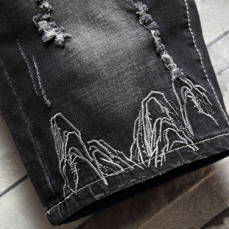 Close-up of black denim shorts featuring intricate eagle embroidery for men's casual fashion.