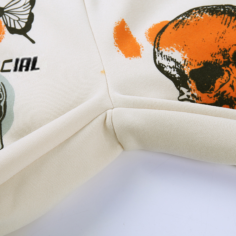 Close-up of stylish graffiti fleece trousers featuring creative skull and butterfly designs in beige fabric.